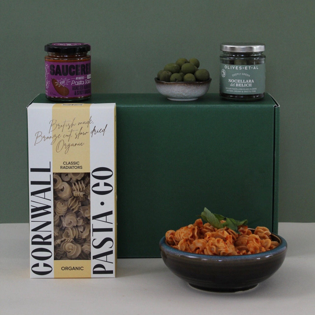 pasta gift box with sauce, pasta in a bowl against a green gift box