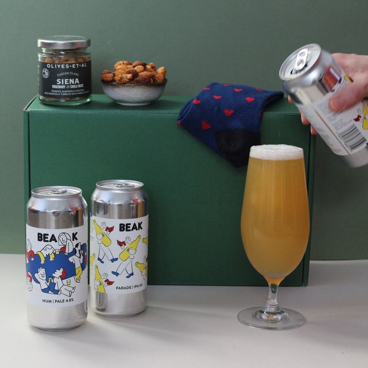pouring beer into a glass against a gift box hamper