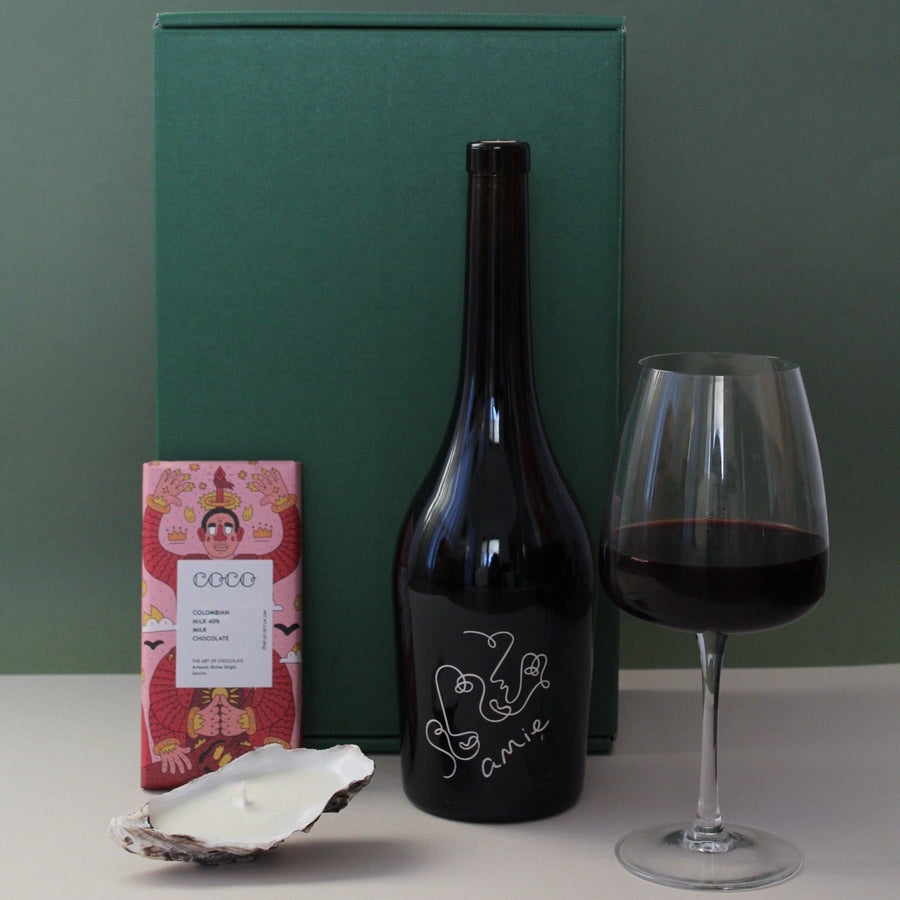 gift box with wine, chocolate and oyster candle against a green backdrop