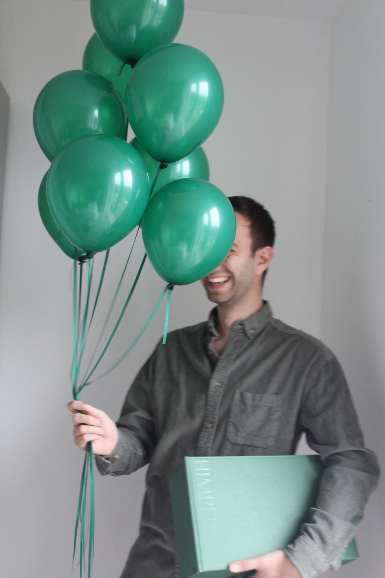 man holding balloons and green gift box