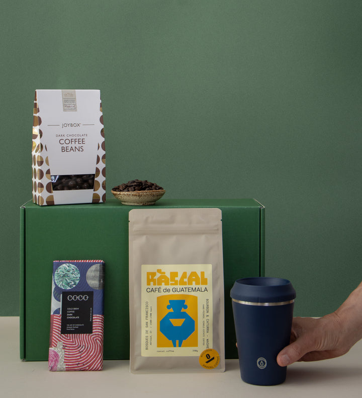 hand holding coffee cup, coffee beans, chocolate and dark chocolate coated coffee beans 